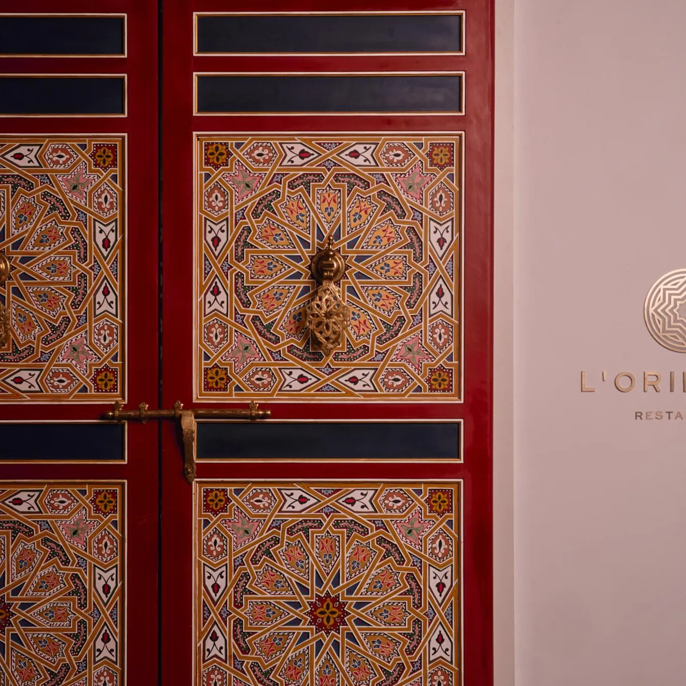Door decorated with colorful geometric patterns with the inscription "L'ORIENTIN RESTAURANT" next to it