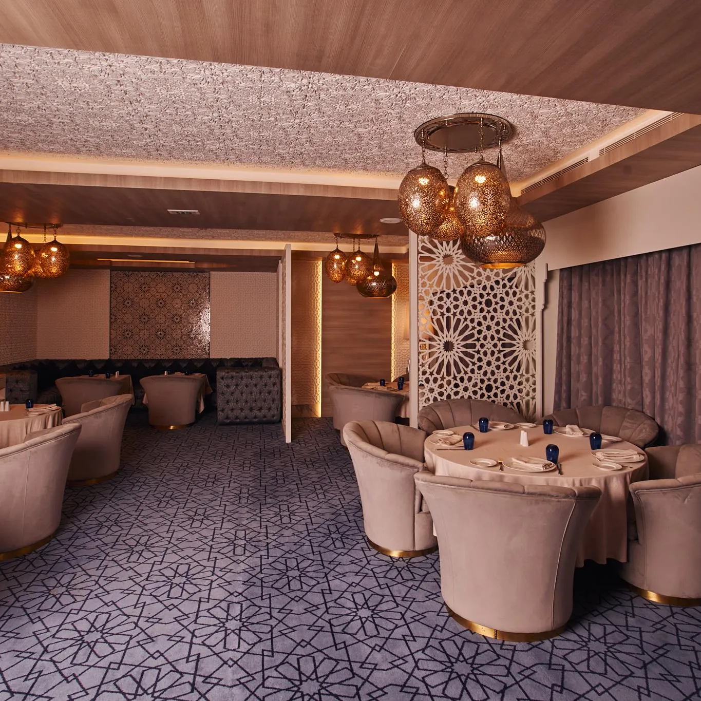Elegant restaurant room with round tables, velvet pink upholstered chairs, and hanging light fixtures
