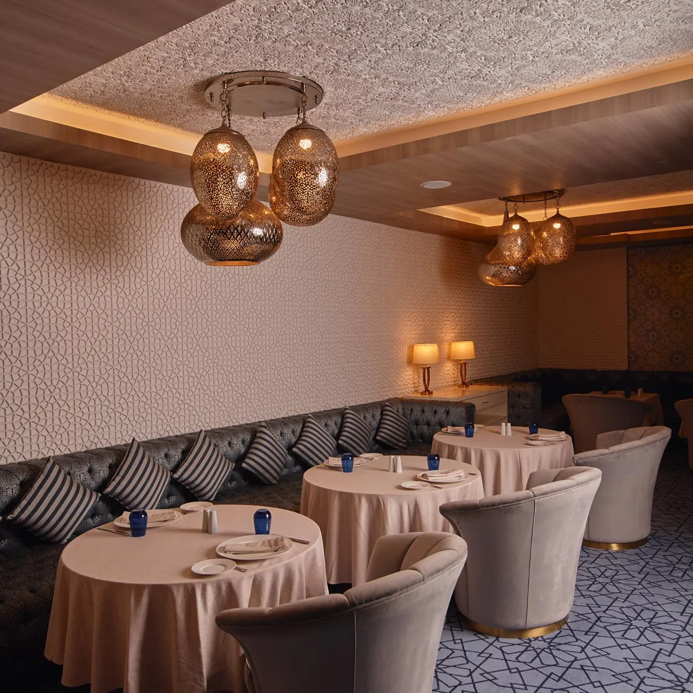 Elegant restaurant room with round tables, upholstered chairs, and hanging lights