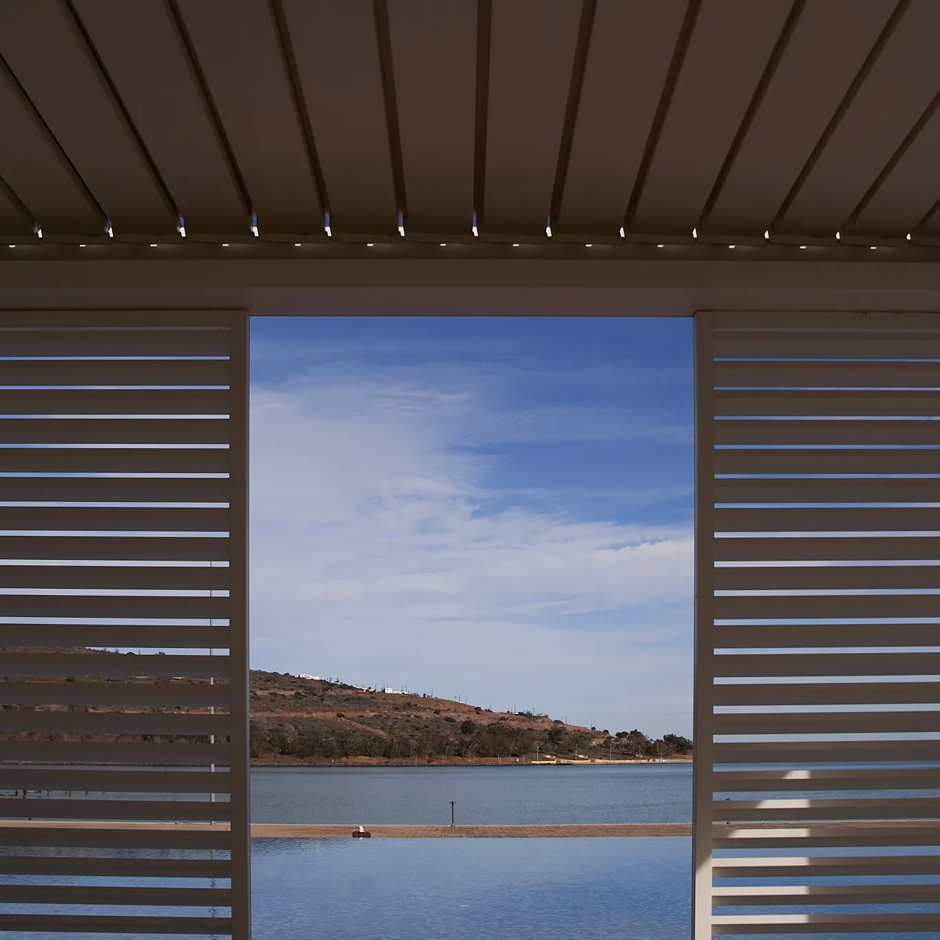 View of a lake and hills through partially open shutters