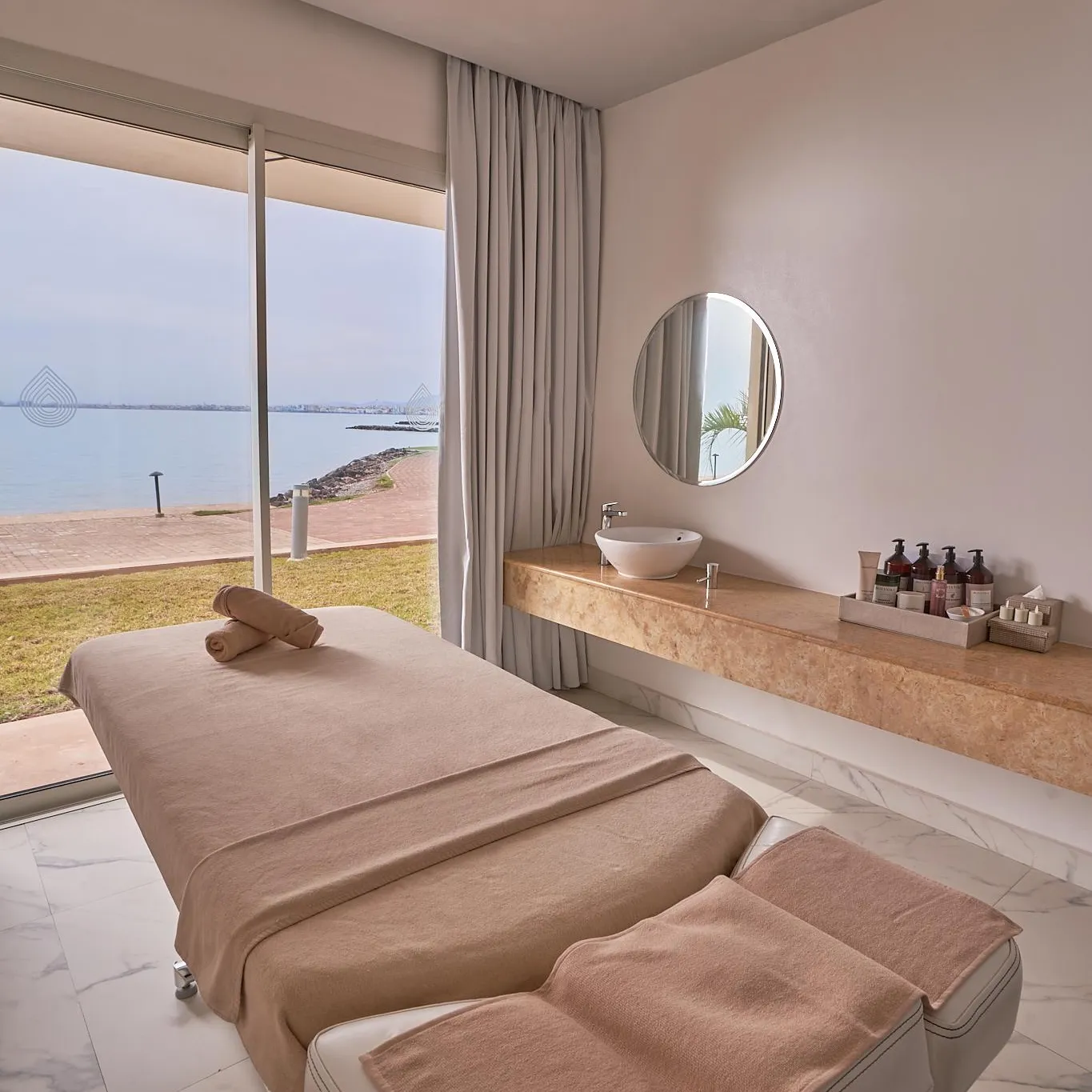Massage room with two treatment tables, a sink, and a sea view