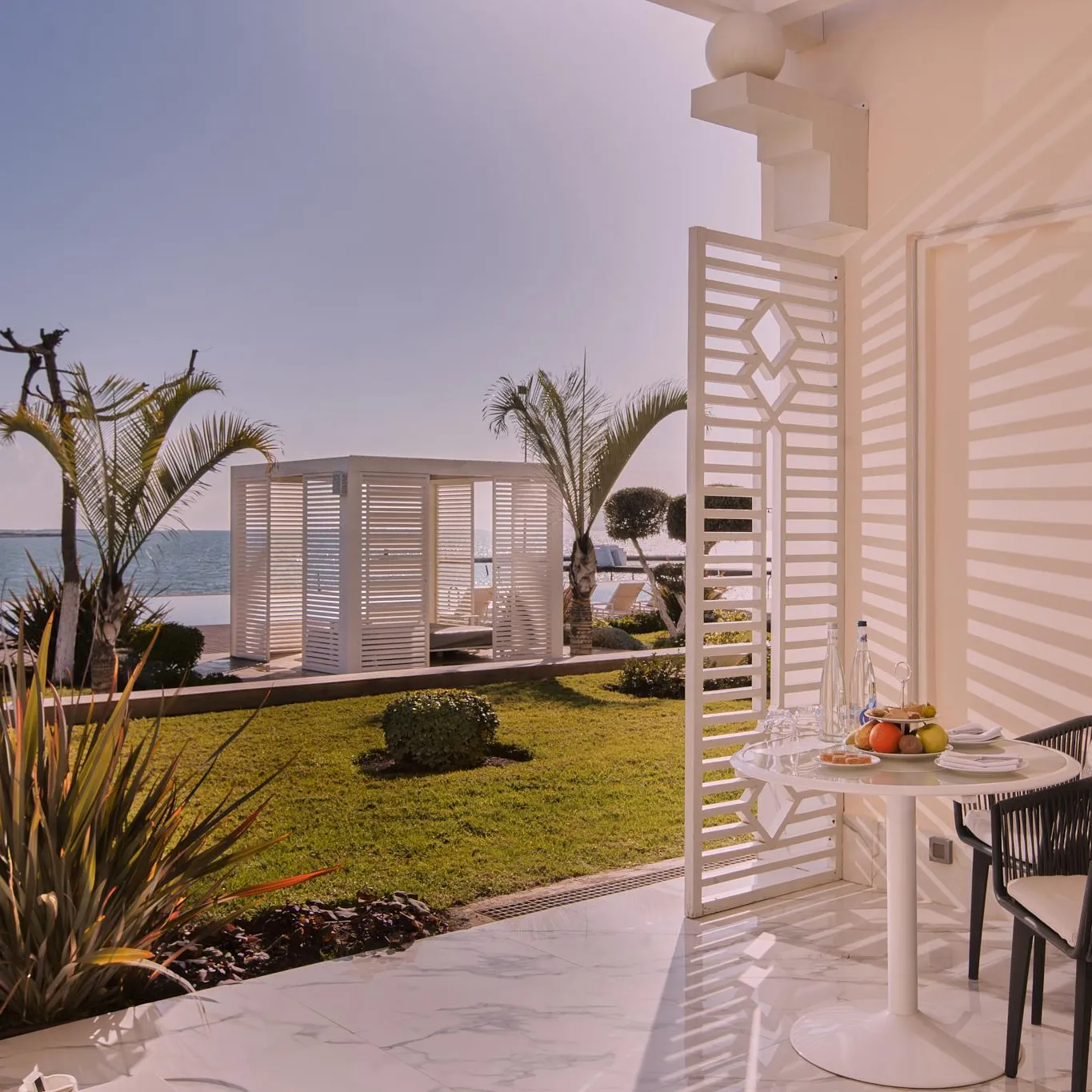 Terrace with table, chairs and plants, sea view with a white building in the background