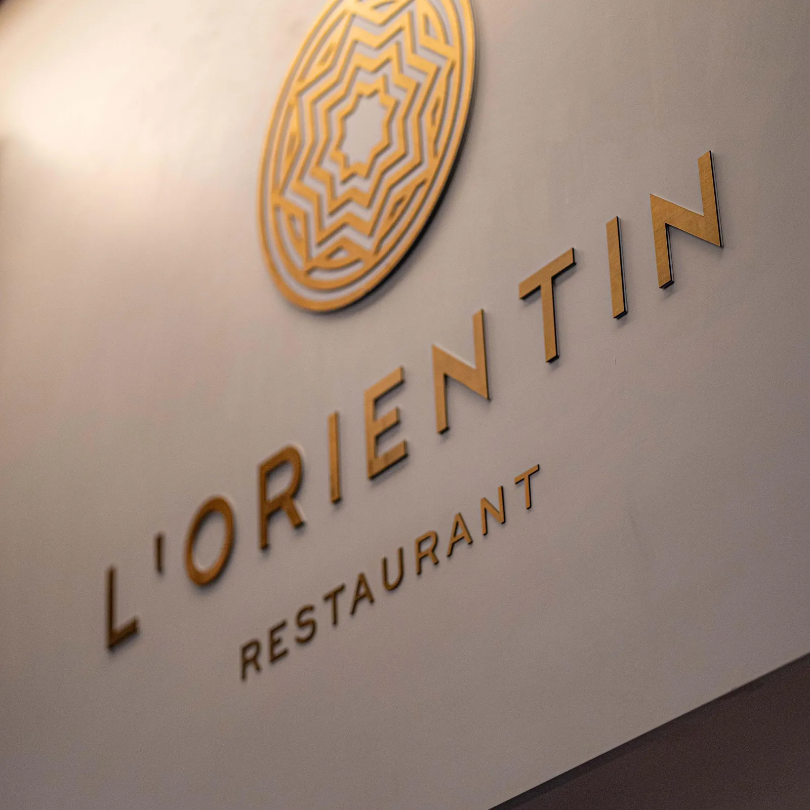 Wall plaque with the logo and the name "L'ORIENTIN RESTAURANT" in gold letters