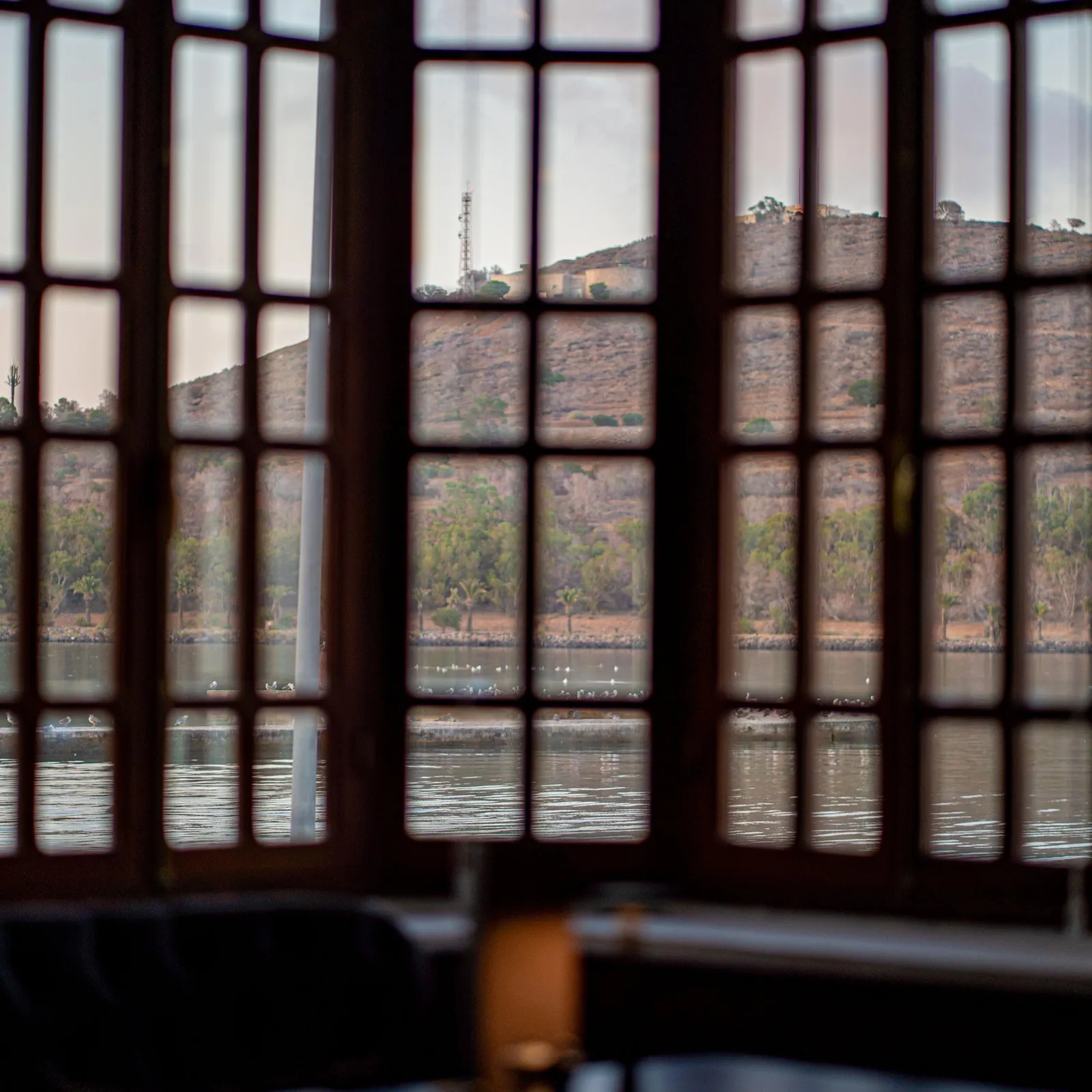 View of an arid landscape through a paneled window, with a river and distant hills