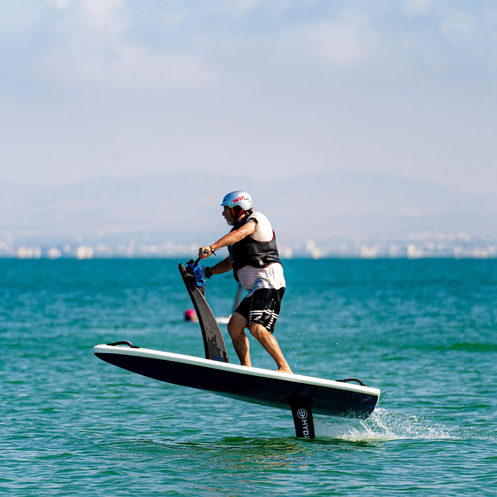 A person in a wetsuit and helmet is hydrofoiling on a board in the sea.