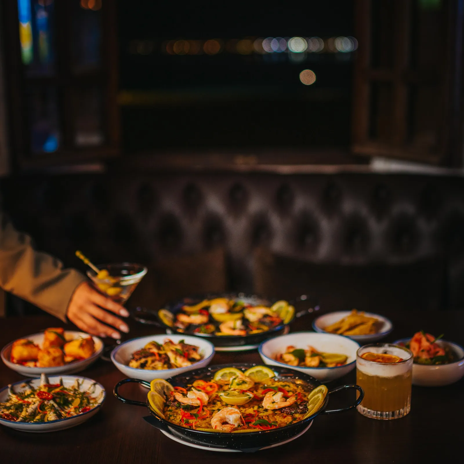 A set of varied dishes and drinks placed on a table in a dimly lit restaurant
