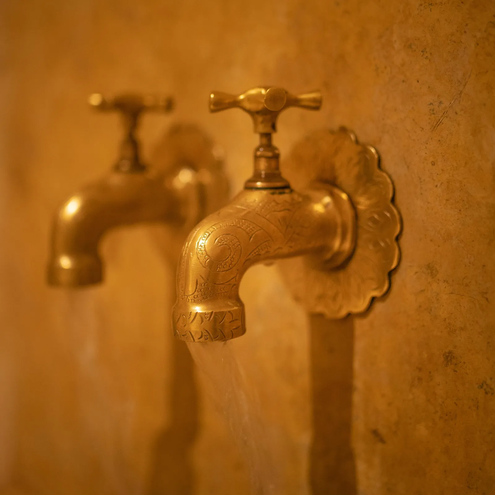 Two metal taps fixed to a concrete wall