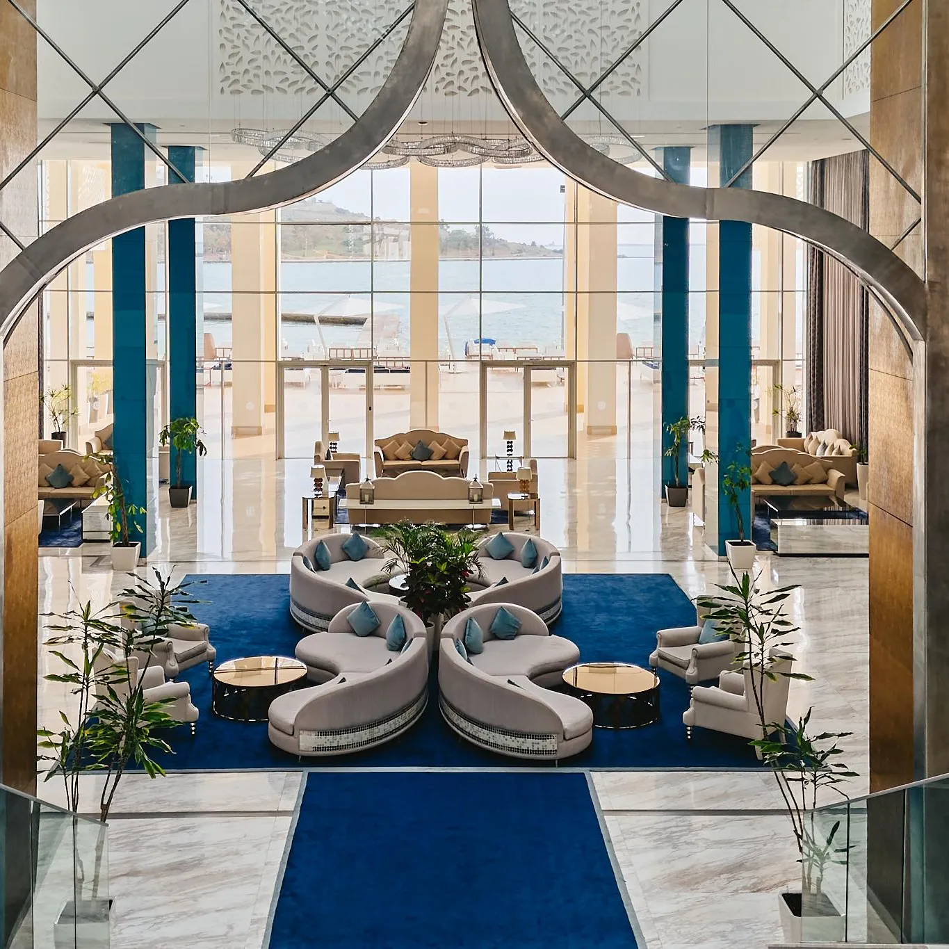 A luxurious interior space with modular sofas, green plants, and a sea view through large windows.