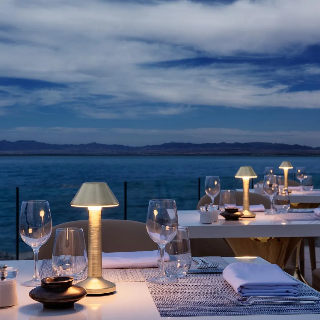 Tables set with glasses and candles on a terrace facing the sea at sunset