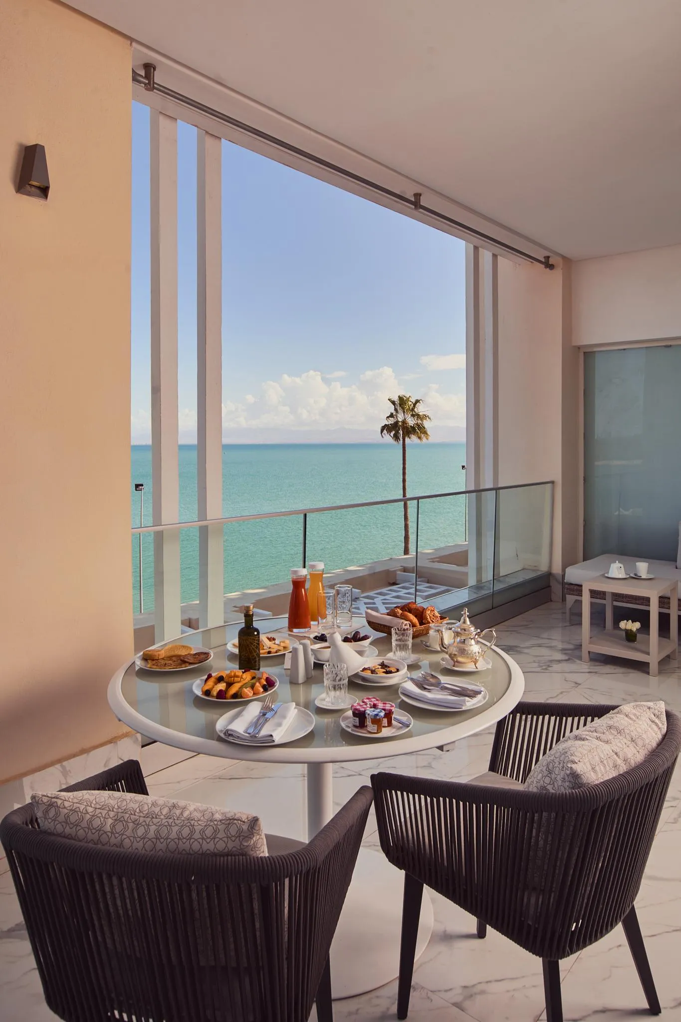 Table ronde avec petit-déjeuner sur un balcon face à la mer, vue sur l'océan et une palme