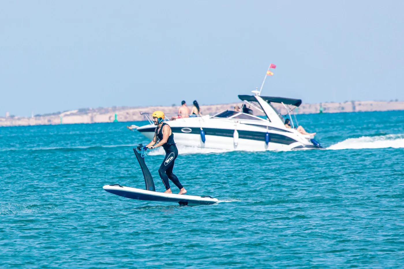 Une personne fait du paddle avec une pagaie dans la mer, un bateau est visible en arrière-plan