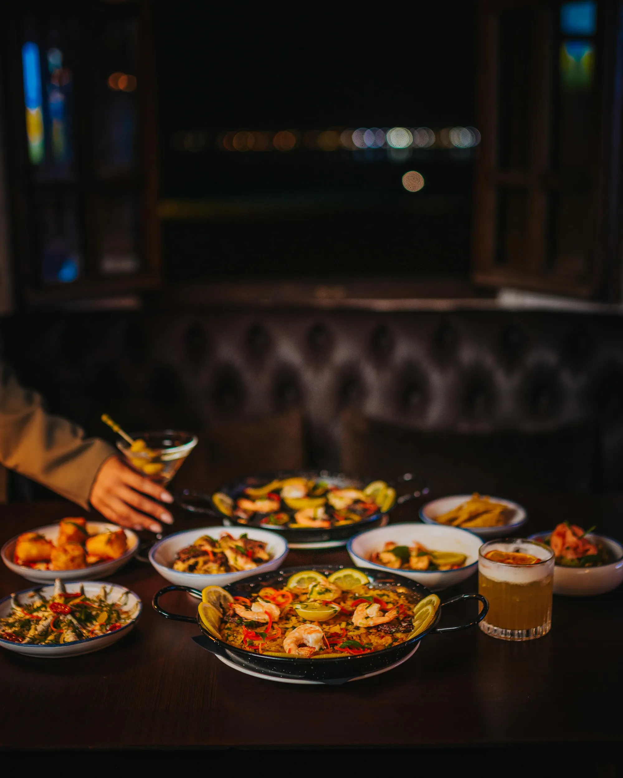 A set of varied dishes and drinks placed on a table in a dimly lit restaurant