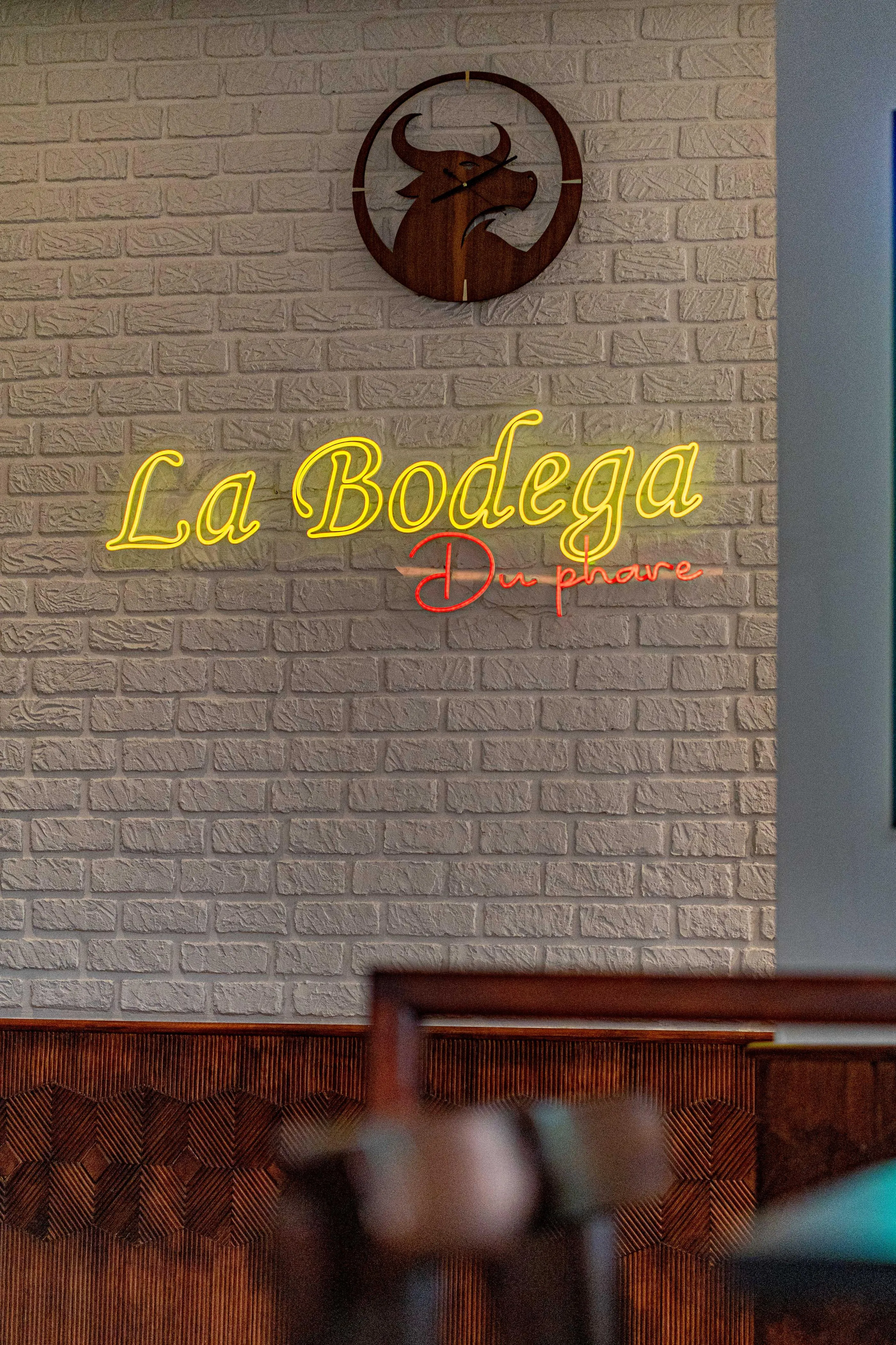 Brick wall with the illuminated sign "La Bodega" and a bull logo above