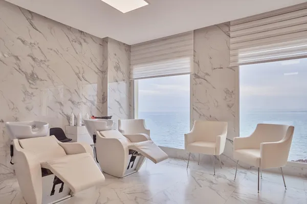 Salon de coiffure moderne avec des fauteuils de coiffure et des chaises, vue sur la mer à travers de grandes fenêtres